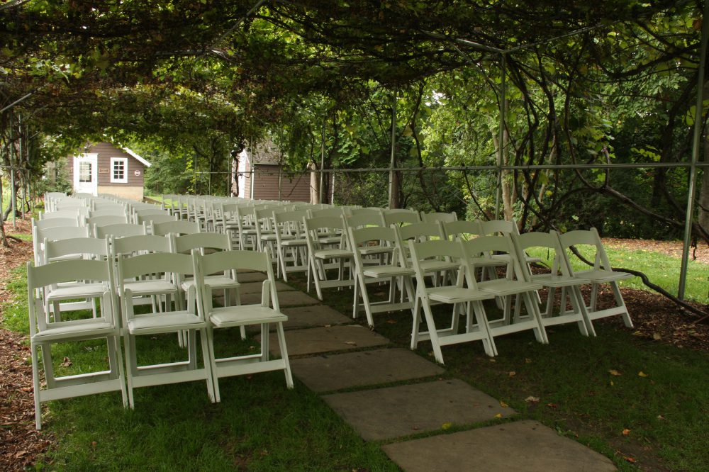 white chairs set up under the grape arbor for ceremony