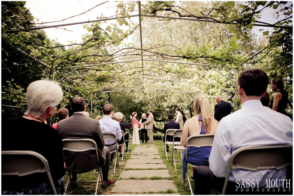 Out Door Wedding Ceremony wedding ceremony under the grape arbor with guests seated looking on