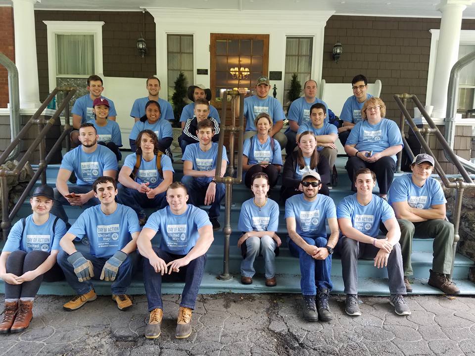 group-of-volunteers-in-blue-shirts-sitting-on-mansion-stairs