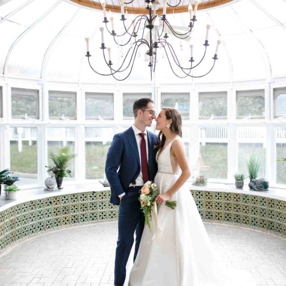 bride and groom standing close in glass conservatory
